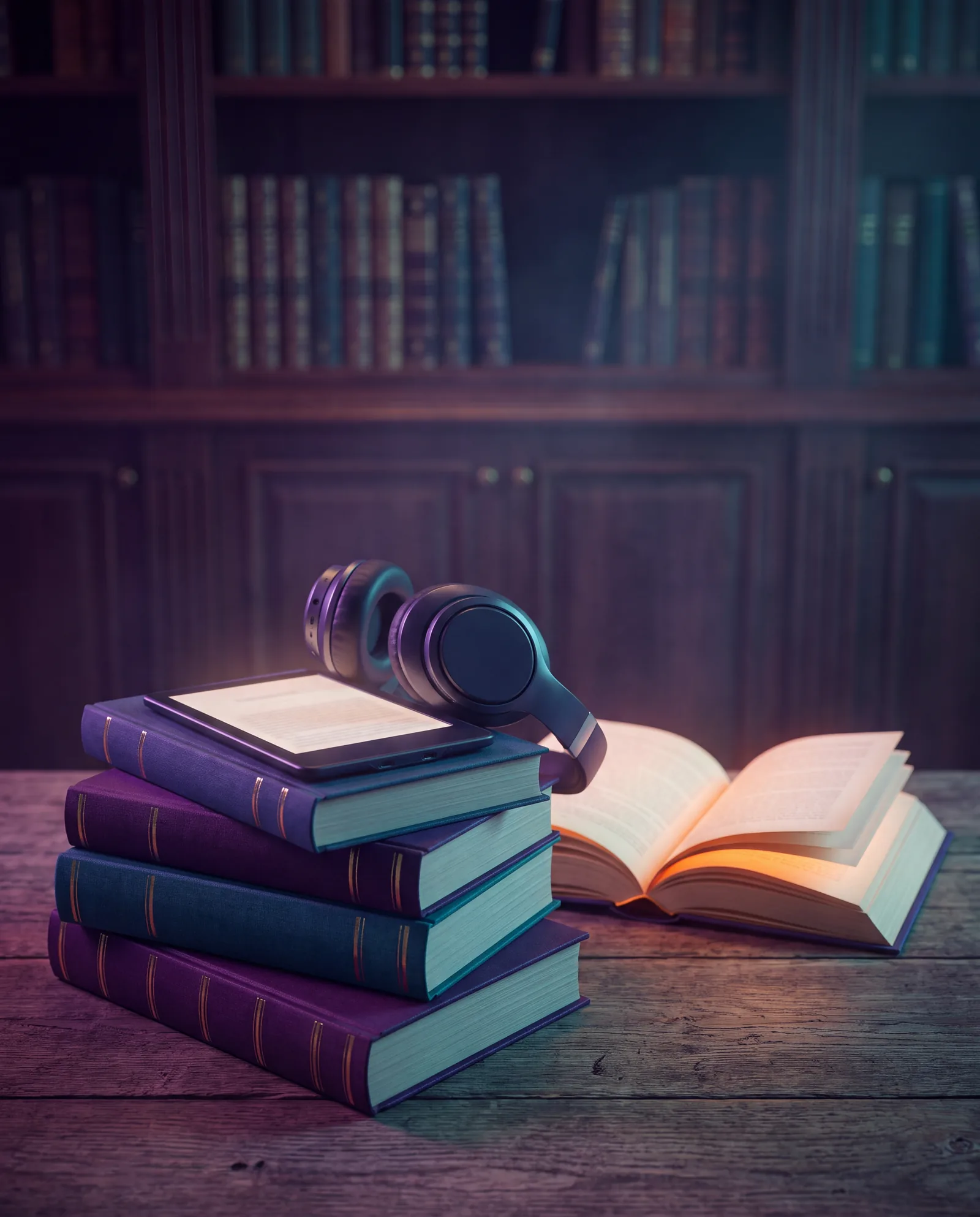 Stack of hardcover books with an e-reader and headphones beside an open glowing book
